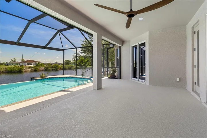 View of swimming pool featuring a water view, a patio, ceiling fan, and a lanai