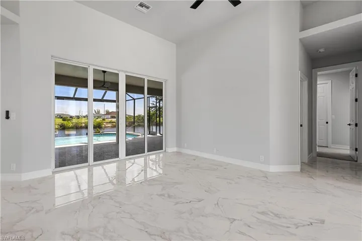 Spare room featuring light tile patterned floors, a towering ceiling, and ceiling fan