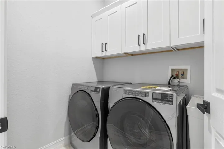 Clothes washing area featuring independent washer and dryer and cabinets