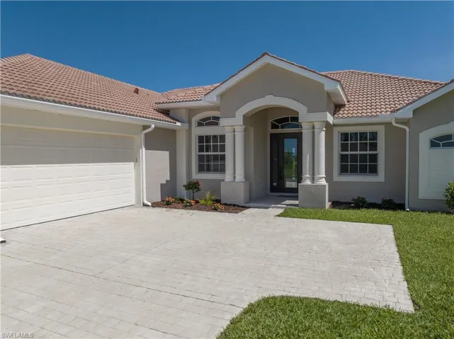 Mediterranean / spanish-style home with a garage and a front lawn