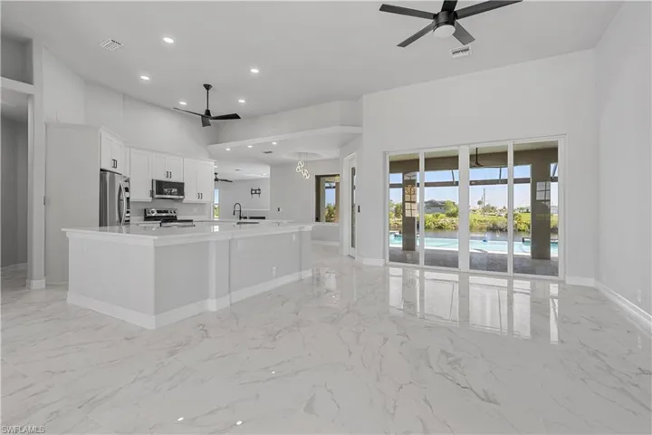 Kitchen with light tile patterned flooring, fridge, ceiling fan, and a spacious island