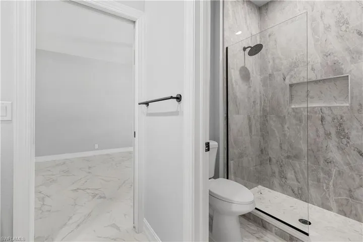 Bathroom with a tile shower, toilet, and tile patterned floors