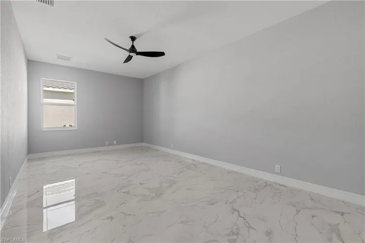 Tiled spare room featuring ceiling fan