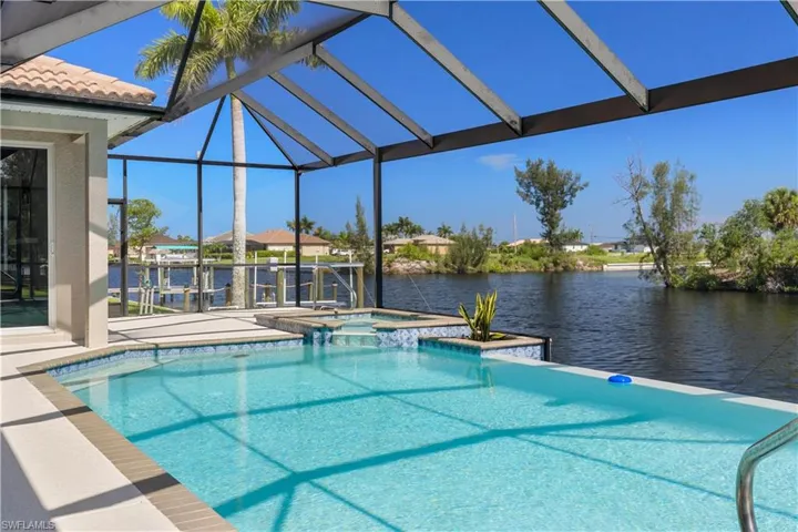 View of pool with an in ground hot tub, a water view, and a lanai