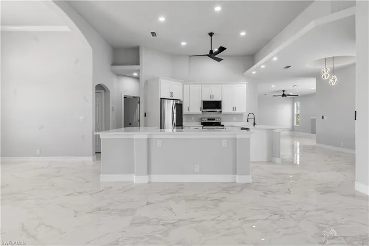 Kitchen featuring a high ceiling, light tile patterned floors, ceiling fan, and stainless steel appliances