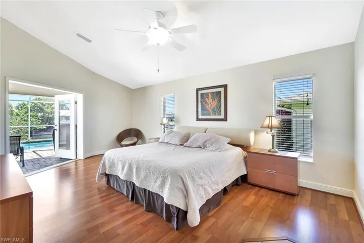Bedroom featuring access to exterior, multiple windows, vaulted ceiling, and light wood-type flooring
