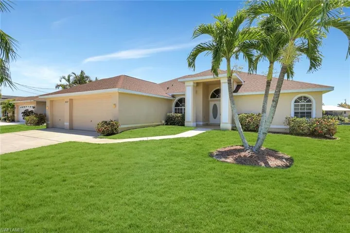 View of front of home with stucco siding, a front lawn, and driveway