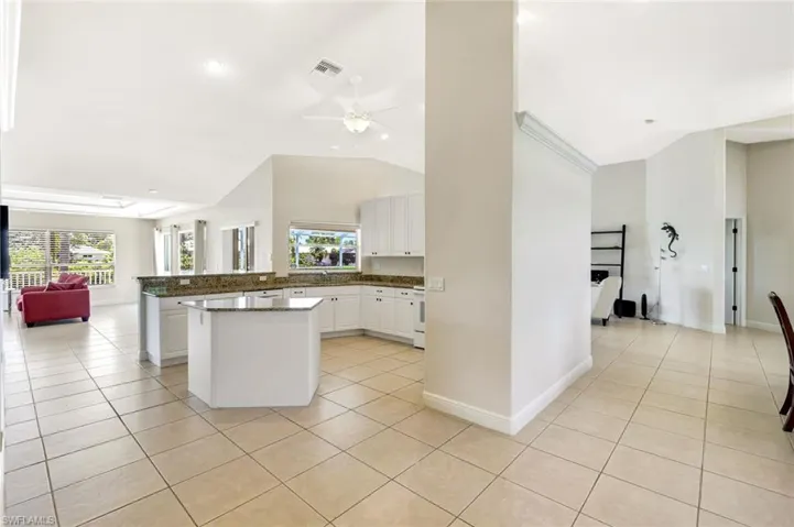Kitchen featuring light tile patterned floors, open floor plan, white cabinetry, high vaulted ceiling, and ceiling fan