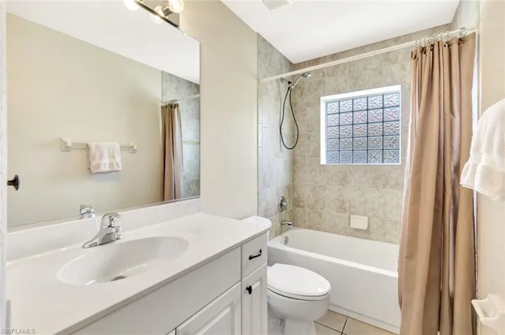 Full bath featuring shower / bathtub combination with curtain, tile patterned floors, vanity, and toilet