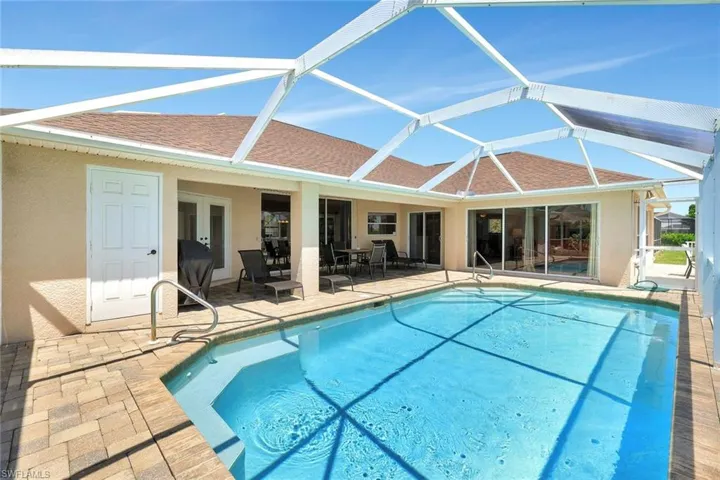 Swimming pool with a patio area, glass enclosure, and french doors
