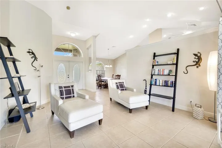 Living room featuring lofted ceiling, light tile patterned flooring, baseboards, and a chandelier