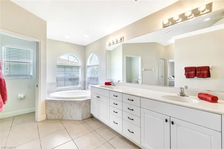 Full bathroom with tile patterned floors, double vanity, a garden tub, and ensuite bathroom