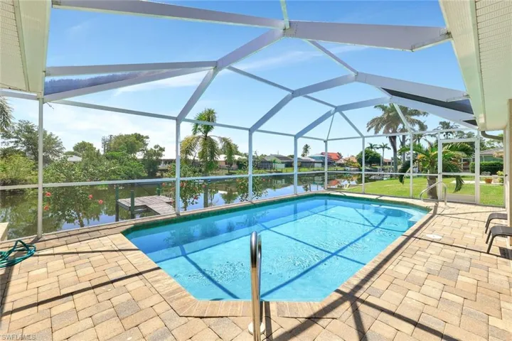 Outdoor pool with a patio area, a water view, and a lanai