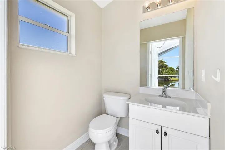 Half bathroom featuring baseboards, toilet, vanity, and tile patterned floors