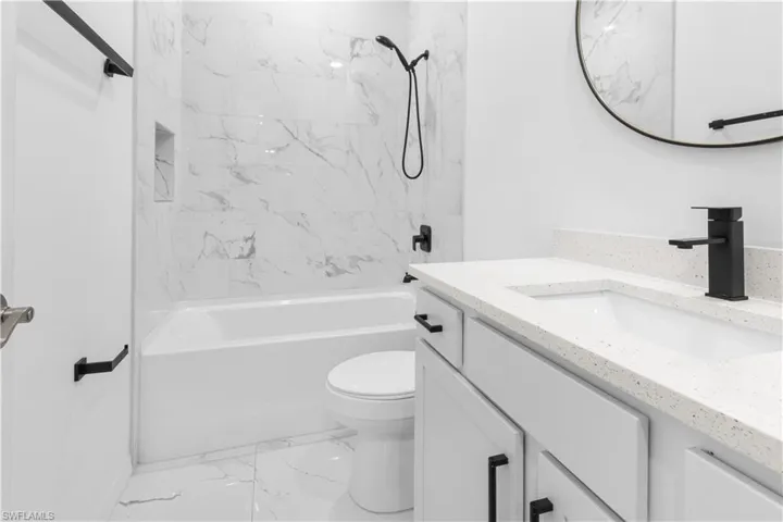 Full bathroom with vanity, tub / shower combination, and light marble finish floors