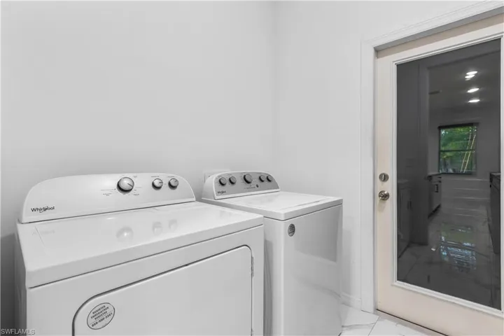 Laundry area featuring marble look tile flooring and washer and clothes dryer