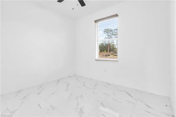 Empty room with marble look tile flooring and ceiling fan