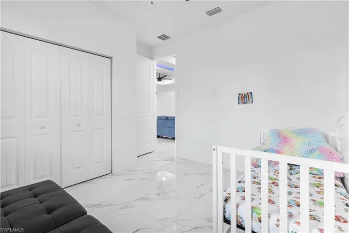Bedroom featuring light marble finish flooring and a closet