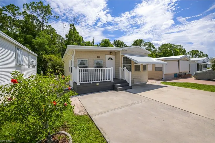 Light-colored siding exterior with white trim, a covered entry porch, and a white awning