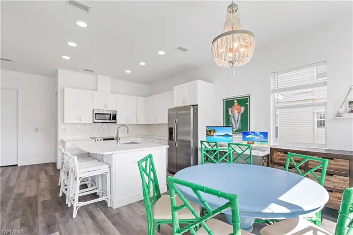 Kitchen with sink, white cabinetry, pendant lighting, a notable chandelier, and appliances with stainless steel finishes