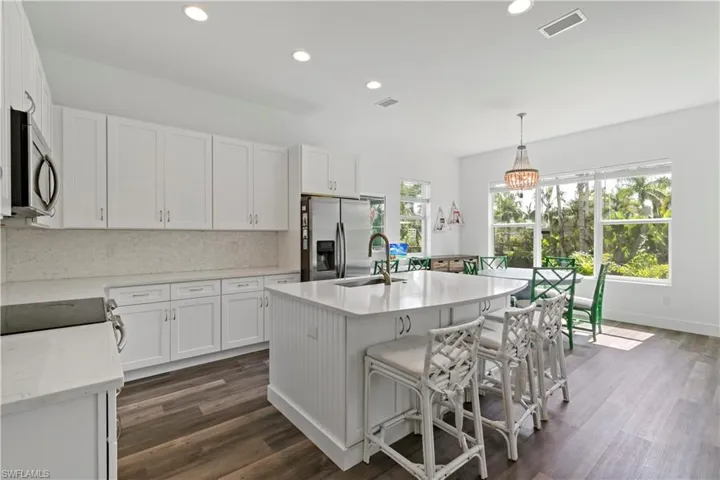 Kitchen featuring appliances with stainless steel finishes, pendant lighting, white cabinets, and sink