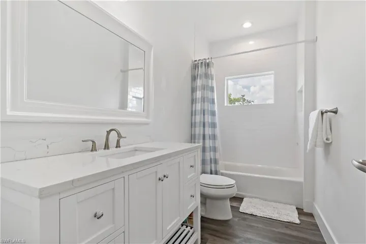 Full bathroom with hardwood / wood-style floors, vanity, toilet, and shower / bath combination with curtain