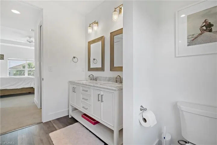 Bathroom with toilet, vanity, ceiling fan, and hardwood / wood-style flooring