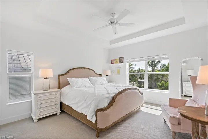 Bedroom featuring ceiling fan, light carpet, and a tray ceiling