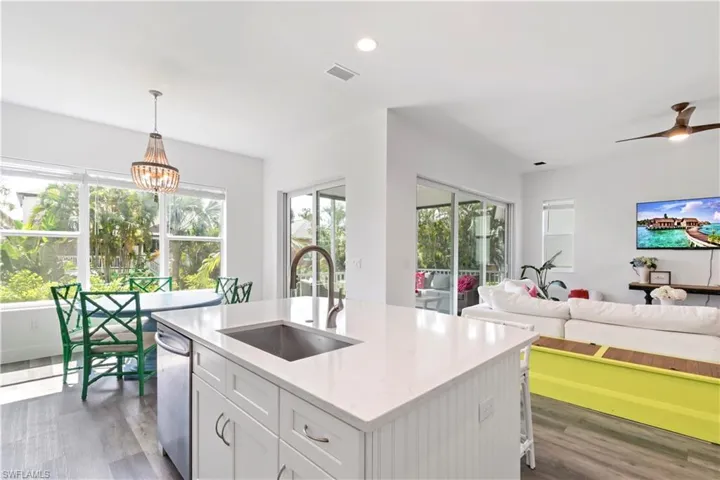 Kitchen with sink, white cabinets, decorative light fixtures, an island with sink, and ceiling fan with notable chandelier