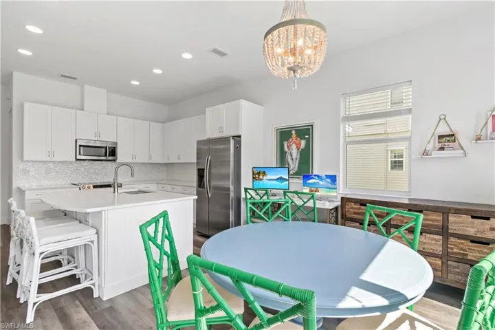Kitchen with pendant lighting, stainless steel appliances, tasteful backsplash, an inviting chandelier, and white cabinets