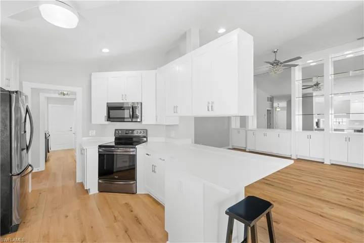Kitchen with stainless steel appliances, a ceiling fan, a peninsula, white cabinets, and recessed lighting