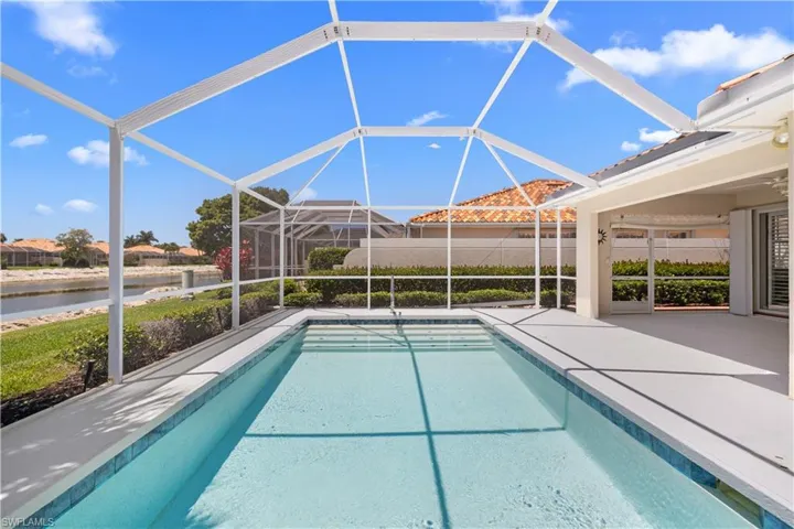 Outdoor pool with a water view, a patio area, and glass enclosure