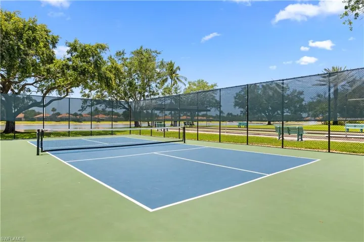 View of tennis court featuring community basketball court and fence