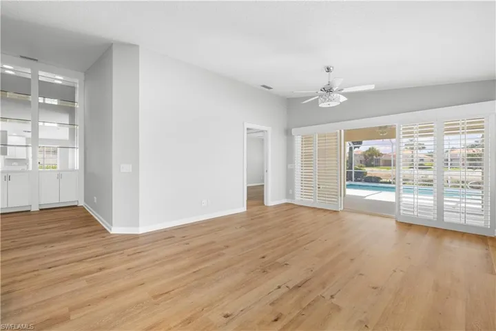 Unfurnished living room featuring ceiling fan, light wood finished floors, and baseboards