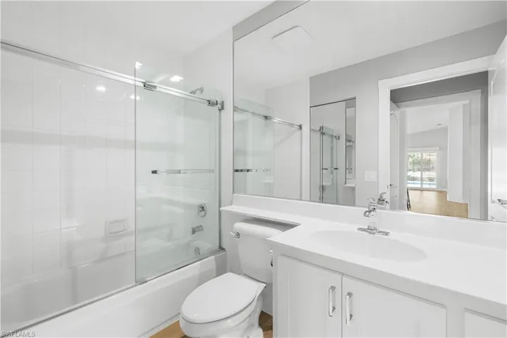 Full bathroom featuring enclosed tub / shower combo, toilet, and vanity