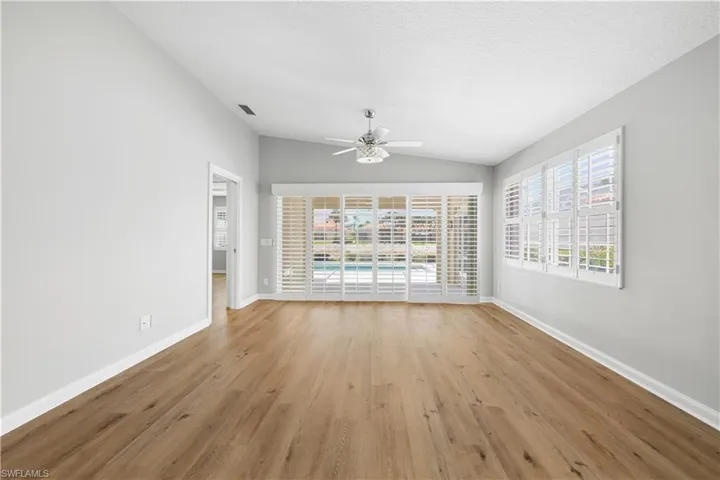 Unfurnished living room with lofted ceiling, a ceiling fan, baseboards, light wood-style flooring, and healthy amount of natural light