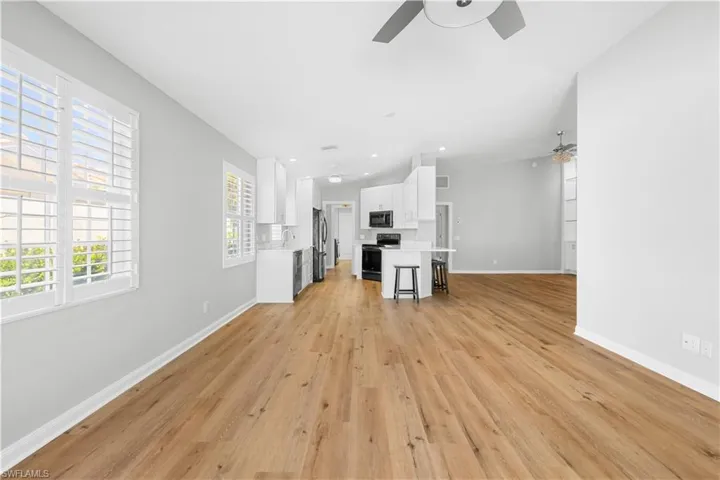 Unfurnished living room featuring ceiling fan, baseboards, light wood finished floors, recessed lighting