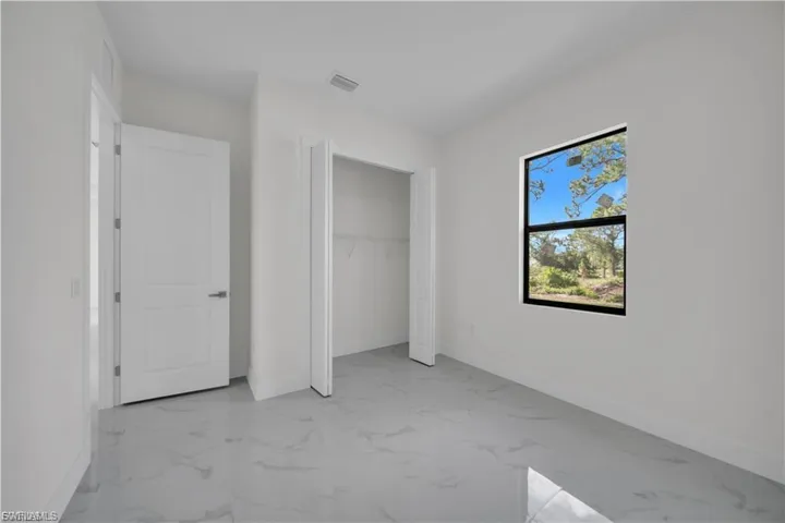 Unfurnished bedroom featuring marble look tiles and a closet