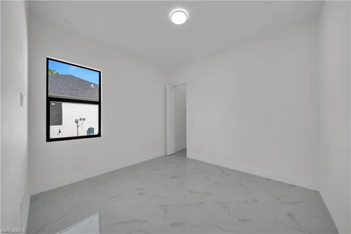 Spare room featuring marble look tile flooring and baseboards