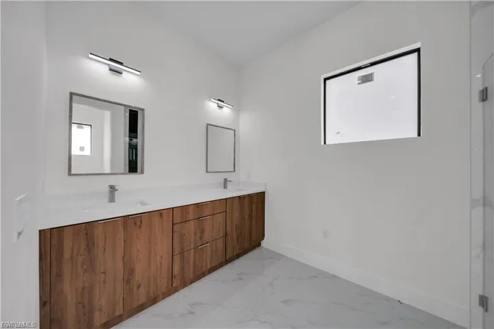 Full bath with marble finish floors and double vanity