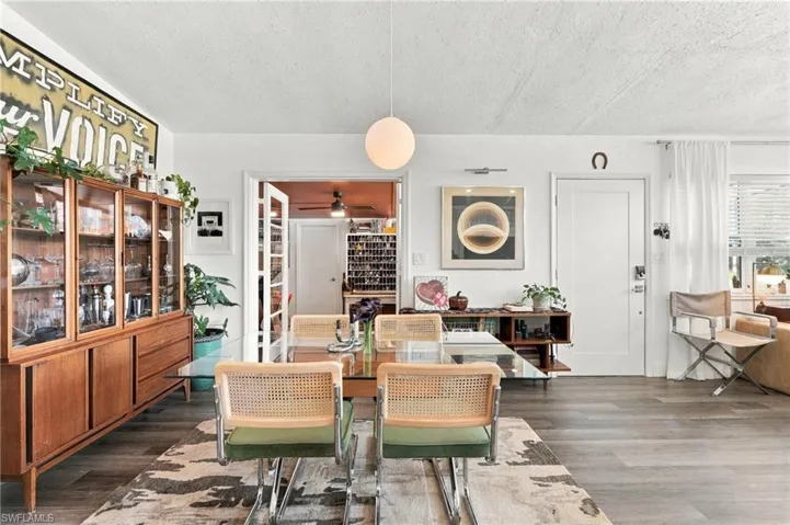Interior space featuring wood-finish flooring, a spherical pendant light fixture, built-in wooden cabinetry, and a multi-pane glass-panel door