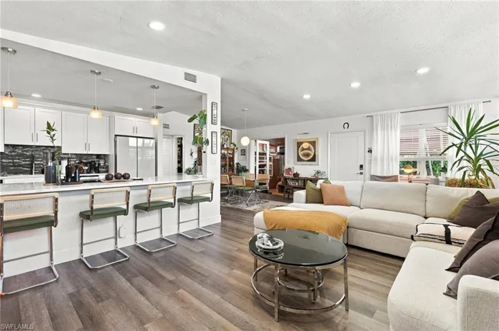 Open-concept interior featuring wood-finish flooring, recessed lighting, and a kitchen peninsula with a stone-surfaced breakfast bar