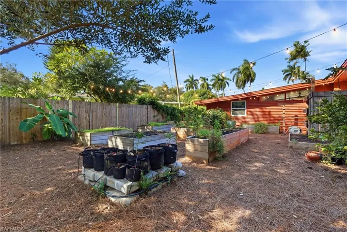 Outdoor space featuring raised garden beds, wood-plank horizontal siding, and string lighting