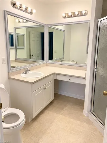 Built-in vanity with integrated sink, expansive mirror, and tile flooring