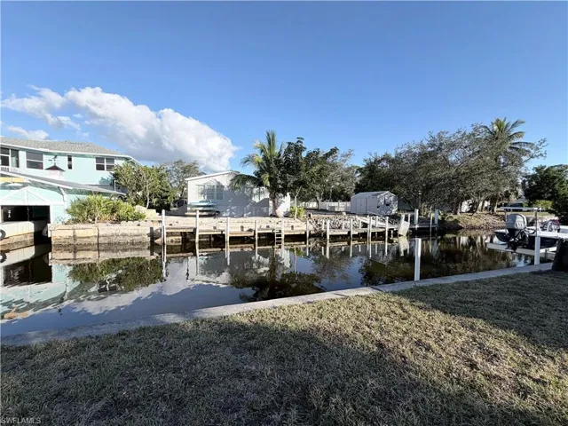 Dock area featuring a water view, a lawn, and a residential view