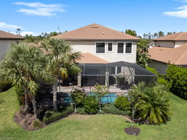 Rear view of property with an outdoor pool, a lawn, a patio, glass enclosure, and a tile roof