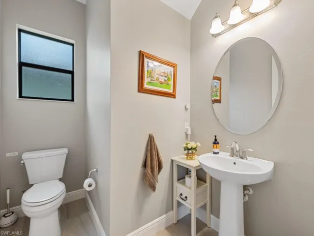 Half bath with baseboards, a sink, and toilet