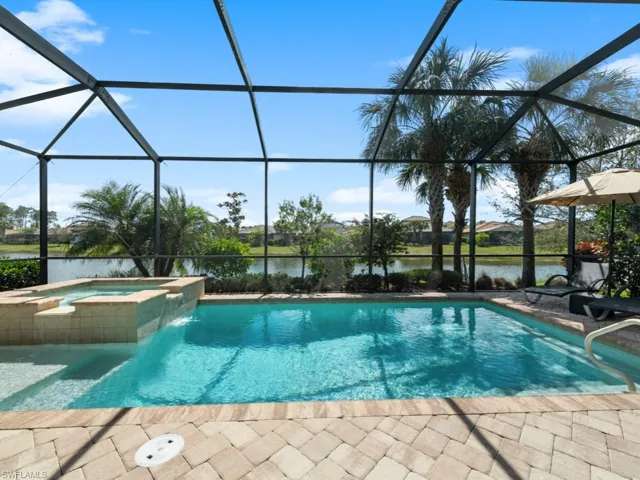 View of pool featuring a patio, a water view, a lanai, and a pool with connected hot tub