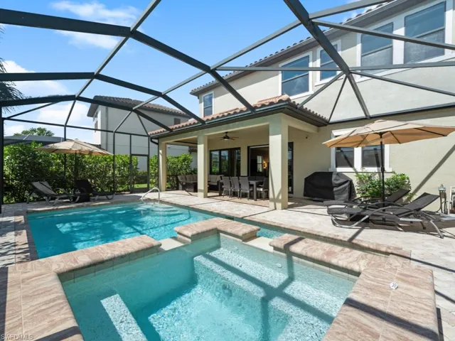 View of swimming pool with ceiling fan, glass enclosure, a pool with connected hot tub, grilling area, and a patio area