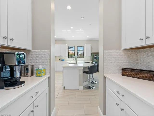 Kitchen featuring recessed lighting, a sink, white cabinets, light countertops, and tasteful backsplash